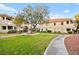 Exterior shot of lush green lawn, walkway, mature tree, and apartment building on a sunny day at 354 Sunward Dr # 354, Henderson, NV 89014