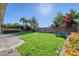 Expansive backyard featuring lush green grass, colorful landscaping, and a brick-paved patio area, perfect for outdoor living at 4087 Villa Rafael Dr, Las Vegas, NV 89141