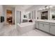Bright bathroom featuring double sinks, a soaking tub, a walk-in shower, and marble tile flooring at 4087 Villa Rafael Dr, Las Vegas, NV 89141
