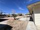Spacious backyard with mature landscaping, concrete patio, and side view of the home's exterior at 4485 Greenhill Dr, Las Vegas, NV 89121