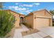 Tan home featuring a two-car garage and a well-manicured lawn at 4963 Pensier St, Las Vegas, NV 89135