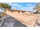 Rear view of a charming home with desert landscape and a chain-link fence, awaiting landscaping and customization at 4970 E Van Buren Ave, Las Vegas, NV 89110