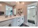 Bright bathroom featuring double sinks, white cabinetry, and a glass-enclosed shower at 524 Teovani St # 826, Henderson, NV 89052