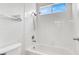 Cozy bathroom featuring white tiled walls, bathtub with shower, and a bright window at 531 Coolidge Ave, Henderson, NV 89015