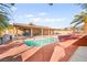 Beautiful pool with rock features, framed by palm trees and a covered patio, great for relaxation at 5717 Christchurch Ave, Las Vegas, NV 89110