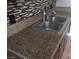 Kitchen featuring a granite countertop, a sink, and mosaic tile backsplash at 6225 Factor Ave, Las Vegas, NV 89107