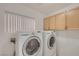 Functional laundry room equipped with a washer, dryer, and overhead storage cabinets at 7228 Buglehorn St, Las Vegas, NV 89131