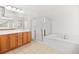 Bright bathroom featuring a bathtub, glass shower, and double vanity sink with cabinet at 11298 Merado Peak Dr, Las Vegas, NV 89135