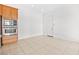 Bright, empty room with a tile floor and a kitchen with stainless steel appliances, and wooden cabinets at 11298 Merado Peak Dr, Las Vegas, NV 89135