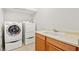 Well-equipped laundry room with a front-load washer, dryer, and utility sink with a wooden cabinet at 11298 Merado Peak Dr, Las Vegas, NV 89135