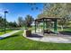 Green community gazebo with picnic tables, set on a well-manicured lawn and surrounded by trees at 1516 Dusty Canyon St, Henderson, NV 89052