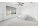 A bright bedroom features neutral carpeting, a ceiling fan, and a large window at 2376 Thelen Ave, North Las Vegas, NV 89086