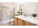 A well-lit bathroom featuring a tub/shower combo with marble walls and a granite vanity at 2575 Evening Twilight Ave, Henderson, NV 89044