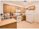 Cozy kitchen with wooden cabinetry, tile floors, and modern white appliances at 2575 Evening Twilight Ave, Henderson, NV 89044
