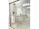 Close-up of a shower with glass doors and gray marble-look tile surround at 2575 Evening Twilight Ave, Henderson, NV 89044
