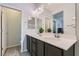 Well lit bathroom features double sinks, dark wood cabinets, a large mirror, and views into toilet room at 320 San Antonio River St, North Las Vegas, NV 89084