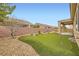 Backyard featuring covered patio, privacy wall, rock landscaping, and putting green at 3220 Flinthead Dr, North Las Vegas, NV 89084