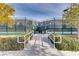 An inviting tennis court entrance with green fencing, landscaping and accessibility ramps on a sunny day at 3220 Flinthead Dr, North Las Vegas, NV 89084