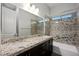 Bathroom with double sinks, dark cabinets, granite countertops, and shower with decorative backsplash at 3870 Valles Caldera Ct, Las Vegas, NV 89118