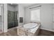 Bathroom showcasing tub with granite surround and tiled shower at 3870 Valles Caldera Ct, Las Vegas, NV 89118