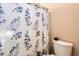 Close up of tub-shower combo featuring a floral curtain and white toilet at 4408 Oasis Hill Ave, North Las Vegas, NV 89085