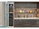 Close up of a bar area featuring a wine refrigerator, sink, and custom cabinetry with lit display shelving at 515 Serenity Point Dr, Henderson, NV 89012