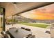 Spacious covered patio with outdoor dining area, lounge furniture, and sunset views over the landscaped backyard at 515 Serenity Point Dr, Henderson, NV 89012