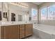 Well-lit bathroom with double vanity, soaking tub, shower, and decorative window at 682 Baffin Island Rd, Henderson, NV 89011