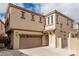 Two-story tan home with a two-car garage, tiled roof, and gated front porch at 682 Baffin Island Rd, Henderson, NV 89011
