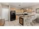 Open kitchen with granite countertops, bar seating, black appliances, and tile floors at 682 Baffin Island Rd, Henderson, NV 89011