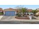 Charming single-story home featuring a terracotta tile roof, mature palm trees, and a blue garage door at 905 White Thunder St, Henderson, NV 89002