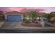 Charming single-story home featuring a terracotta tile roof, mature palm trees, and a blue garage door at 905 White Thunder St, Henderson, NV 89002