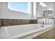 Close up of bathtub with tile surround, mosaic backsplash, and window with natural light at 9570 Verde Way, Las Vegas, NV 89149