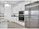 A bright kitchen features stainless steel appliances, white cabinets, a built-in oven and a refrigerator at 9570 Verde Way, Las Vegas, NV 89149