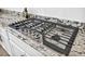 Close-up of a stovetop with stainless steel knobs and a granite countertop at 9570 Verde Way, Las Vegas, NV 89149