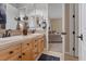 Bathroom featuring double sinks with tan tile counters and cabinetry, plus an open doorway to the home's living area at 9668 Doraville Ave, Las Vegas, NV 89149