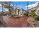 A well-manicured front yard with a curved walkway, desert landscaping and mature trees at 9668 Doraville Ave, Las Vegas, NV 89149