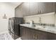 Well-organized laundry room with cabinetry, stainless steel sink, and modern washer/dryer at 9938 Regency Canyon Way, Las Vegas, NV 89148