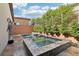 Backyard spa and water feature surrounded by greenery and travertine tile at 9938 Regency Canyon Way, Las Vegas, NV 89148