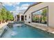 Relaxing pool and spa combination with waterfall feature and covered outdoor kitchen in background at 9938 Regency Canyon Way, Las Vegas, NV 89148