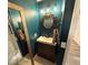 Stylish half bath featuring a vanity with updated fixtures, an ornate mirror and decorative paint at 10323 Hardy Falls St, Las Vegas, NV 89141