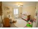 Bright Bedroom features a cozy chair, crib with canopy, decorative signs and a soft rug at 10323 Hardy Falls St, Las Vegas, NV 89141