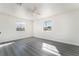 Sunlit bedroom with gray laminate floors, a ceiling fan, and two windows at 116 W Victory Rd, Henderson, NV 89015