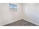 A bright bedroom featuring gray laminate flooring, a window with security bars, and neutral paint at 116 W Victory Rd, Henderson, NV 89015