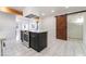 Bright kitchen showcasing a black island with gold hardware, marble floors, and a rustic sliding barn door at 116 W Victory Rd, Henderson, NV 89015