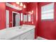 Bold bathroom with white vanity, sink, and a large mirror, complemented by striking red walls at 1892 Falcon Ridge St, Las Vegas, NV 89142