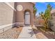 Arched entryway with a white front door, desert plants, and a decorative fence for a charming welcome at 1892 Falcon Ridge St, Las Vegas, NV 89142