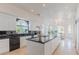 Open kitchen design with a large island, white cabinetry, and black countertops leading to a dining area at 2339 Prometheus Ct, Henderson, NV 89074