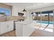 Modern, white kitchen with an island, stainless steel appliances, and window overlooking the backyard pool at 2547 Wolverton Ave, Henderson, NV 89074