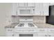 Clean white stove and microwave with granite countertops and a tile backsplash at 3975 N Hualapai Way # 235, Las Vegas, NV 89129